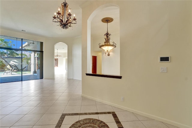 unfurnished room featuring baseboards, arched walkways, a notable chandelier, and light tile patterned flooring