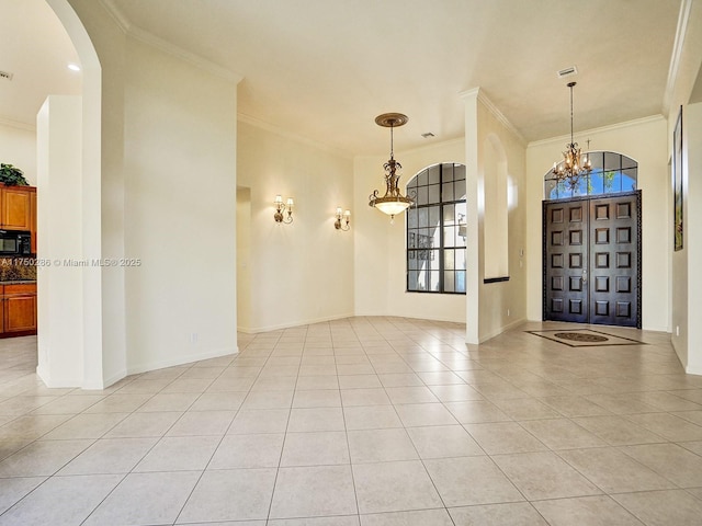 foyer with light tile patterned floors, a notable chandelier, arched walkways, and crown molding