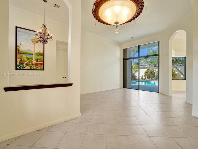 spare room featuring light tile patterned floors, arched walkways, visible vents, baseboards, and crown molding