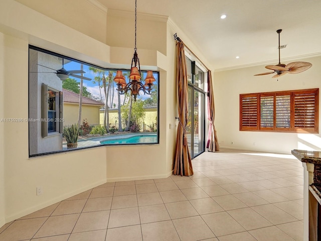 unfurnished dining area with ceiling fan with notable chandelier, ornamental molding, tile patterned flooring, and baseboards