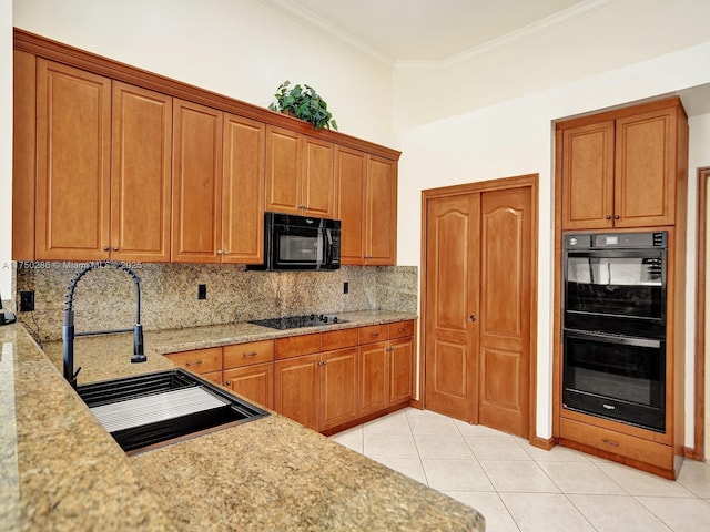 kitchen with a sink, brown cabinets, decorative backsplash, black appliances, and crown molding