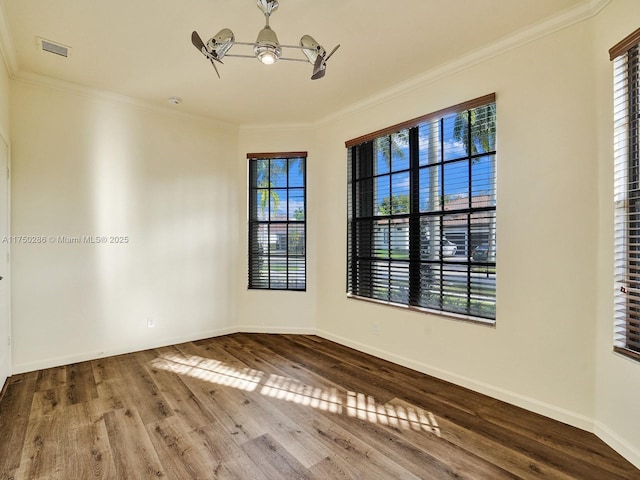 unfurnished room featuring wood finished floors, visible vents, and crown molding