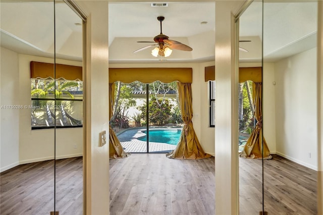 entryway featuring ceiling fan, wood finished floors, visible vents, and baseboards