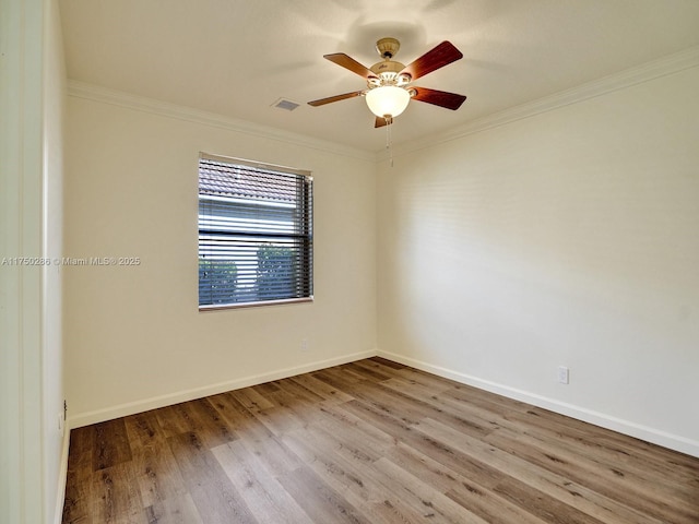 spare room with visible vents, crown molding, baseboards, and wood finished floors