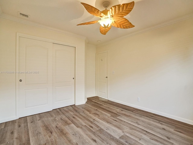 unfurnished bedroom featuring baseboards, a closet, wood finished floors, and crown molding