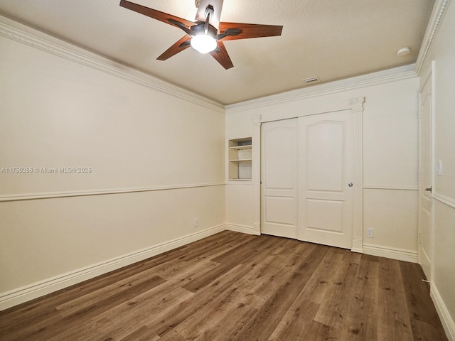 unfurnished bedroom featuring crown molding, a closet, baseboards, and wood finished floors