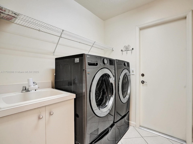 clothes washing area featuring separate washer and dryer, light tile patterned flooring, a sink, and cabinet space