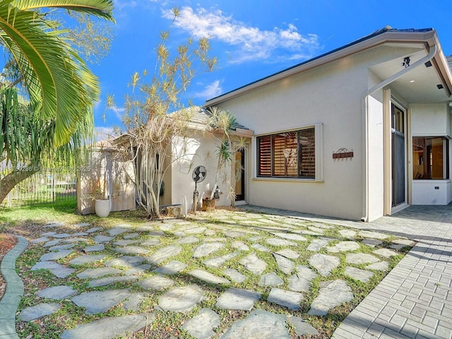 exterior space with a patio, fence, and stucco siding