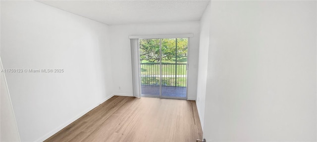 empty room with light wood-type flooring, a textured ceiling, and baseboards