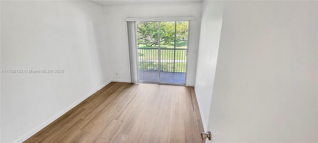 spare room with baseboards and wood finished floors