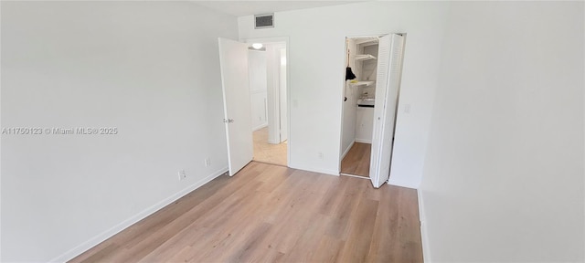 unfurnished bedroom featuring visible vents, a closet, light wood-style flooring, and baseboards