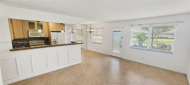 kitchen featuring hanging light fixtures, glass insert cabinets, a chandelier, white appliances, and a peninsula