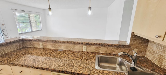 kitchen with decorative light fixtures, a sink, and backsplash