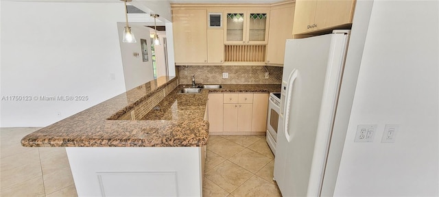 kitchen featuring white appliances, visible vents, glass insert cabinets, a peninsula, and a sink