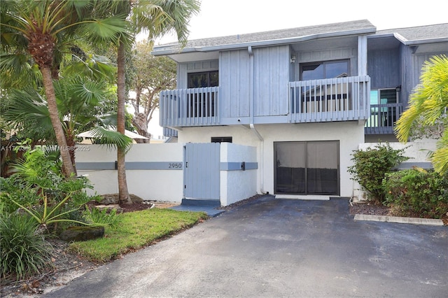 view of front of home featuring a garage, a balcony, a gate, fence, and stucco siding