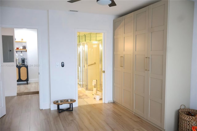 bedroom featuring a closet, visible vents, ensuite bathroom, light wood-style floors, and electric panel