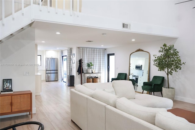 living room with baseboards, light wood finished floors, visible vents, and recessed lighting