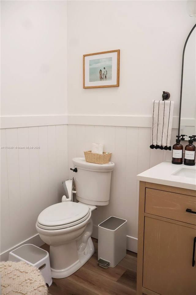 bathroom featuring a wainscoted wall, vanity, toilet, and wood finished floors