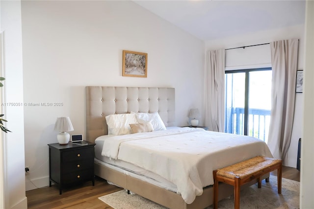 bedroom with lofted ceiling, access to exterior, and wood finished floors