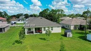 back of property with an outbuilding, a lawn, and a storage unit