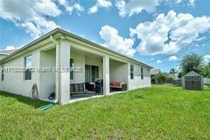 rear view of house featuring a lawn and a storage unit