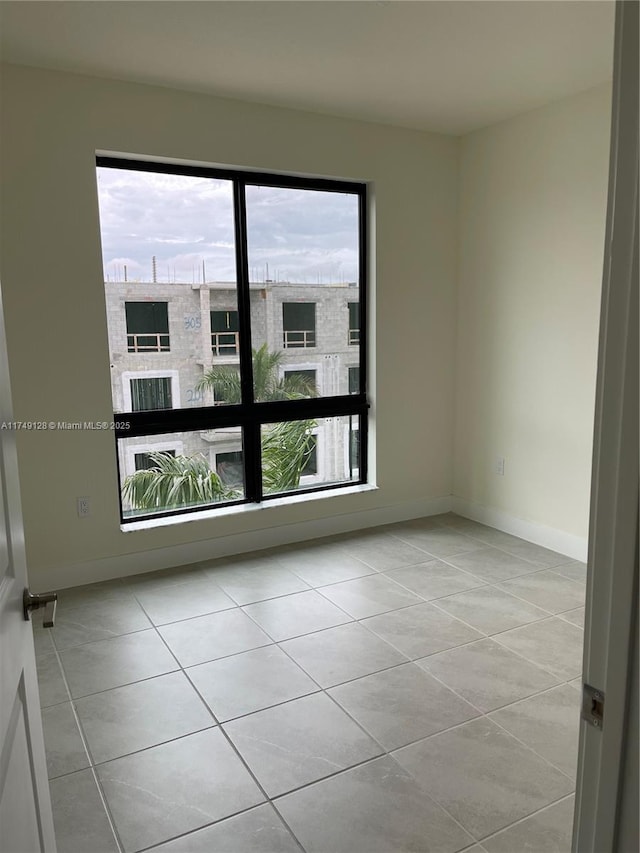 unfurnished room with light tile patterned floors and baseboards