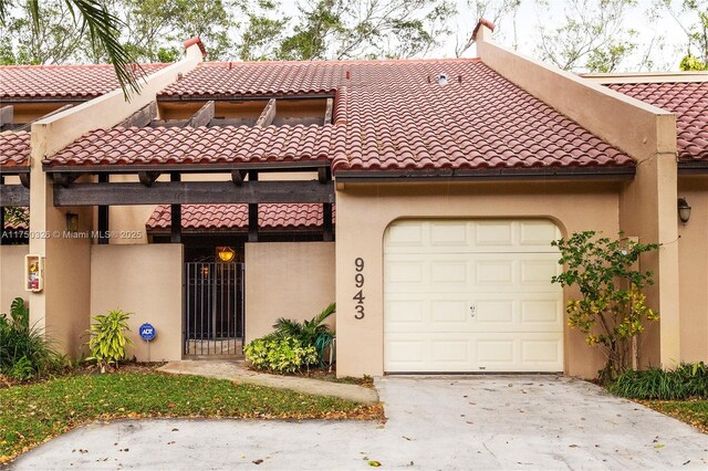 view of front of property with a garage, a tiled roof, concrete driveway, and stucco siding