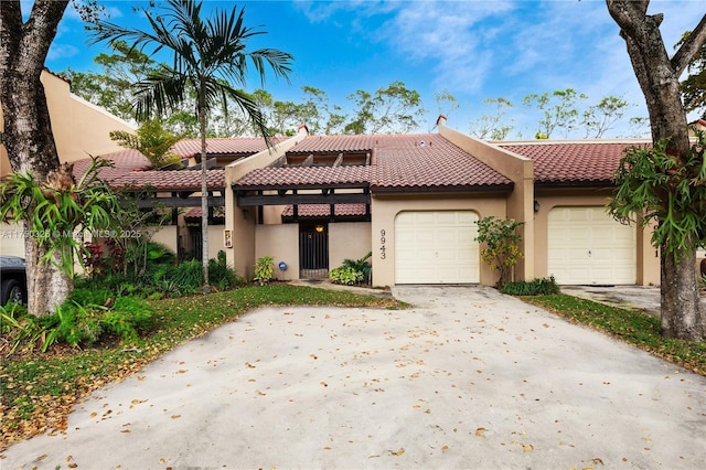 view of front of property with concrete driveway, an attached garage, a tiled roof, and stucco siding