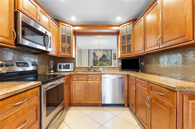 9943 Costa Del Sol Blvd Unit B-108A, Doral, FL 33178 - kitchen with stainless steel appliances, brown cabinets, light tile patterned floors, decorative backsplash, and light stone countertops
