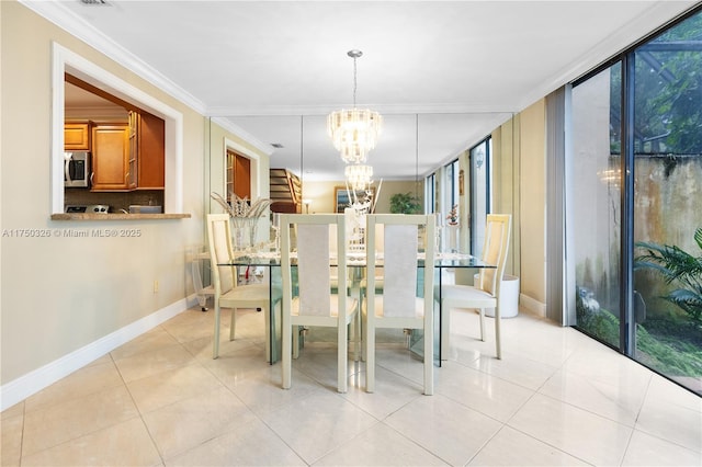 dining room with a notable chandelier, light tile patterned floors, ornamental molding, a wall of windows, and baseboards