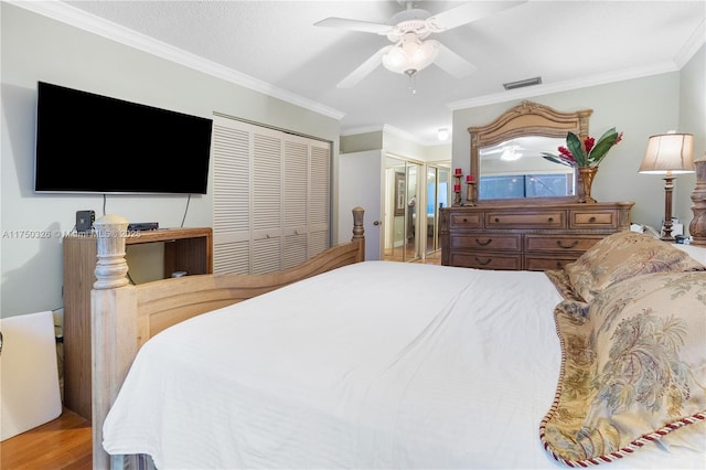 bedroom featuring wood finished floors, a ceiling fan, multiple closets, visible vents, and crown molding