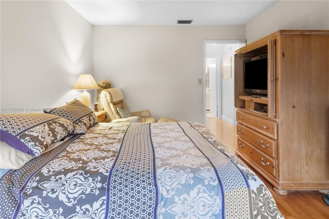 bedroom with visible vents, light wood-style flooring, and a textured ceiling