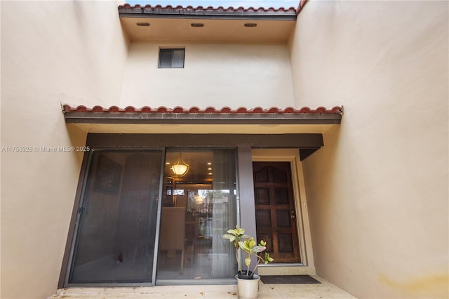 doorway to property with a tile roof and stucco siding