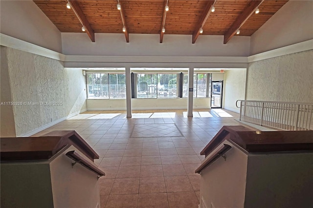 spare room with light tile patterned floors, wooden ceiling, beamed ceiling, rail lighting, and a high ceiling