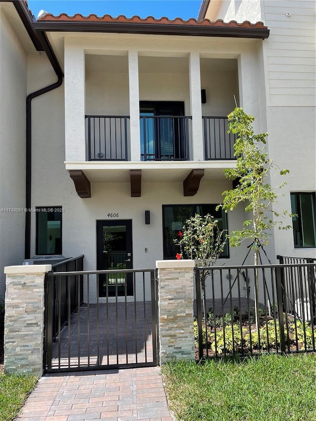 exterior space with a tile roof, fence, a gate, and stucco siding