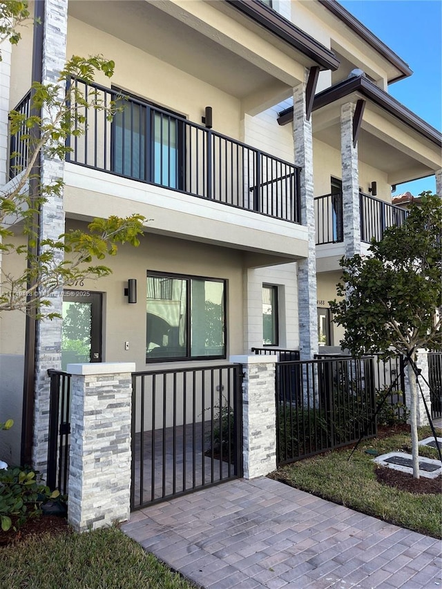 view of front facade featuring fence, a balcony, and stucco siding