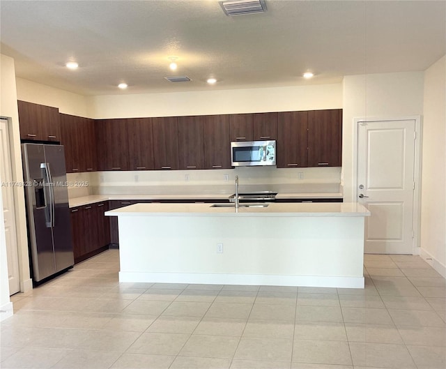 kitchen featuring visible vents, light countertops, appliances with stainless steel finishes, and a center island with sink