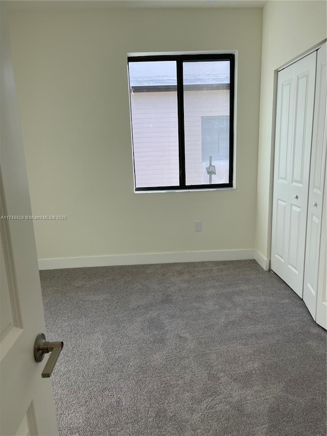 unfurnished bedroom with carpet floors, a closet, and baseboards