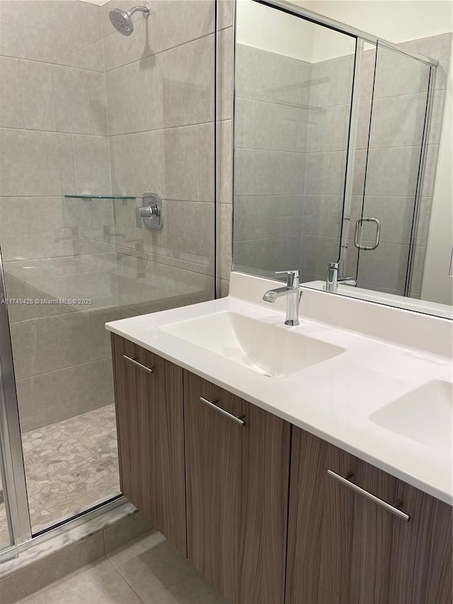 bathroom featuring double vanity, a stall shower, a sink, and tile patterned floors