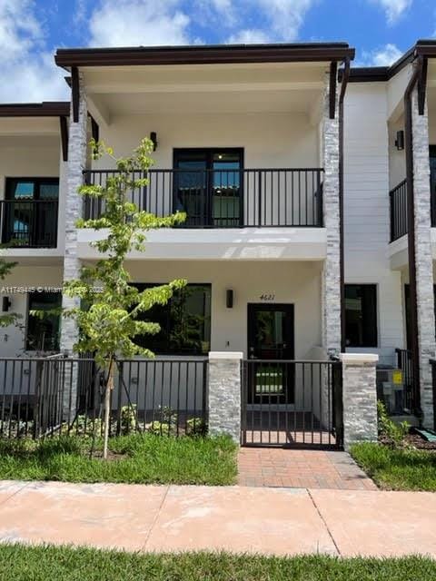 view of front of home featuring a fenced front yard, a balcony, and stucco siding