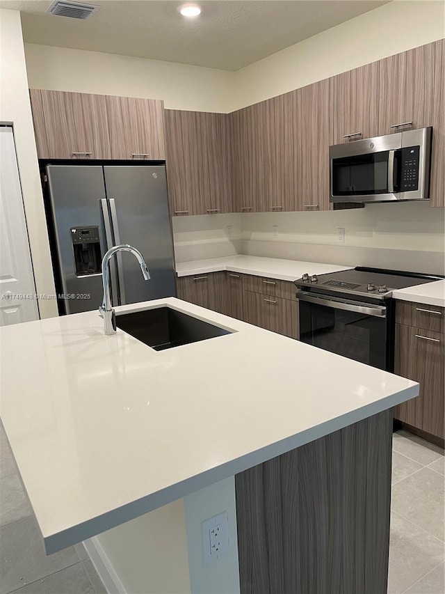 kitchen with light tile patterned floors, modern cabinets, stainless steel appliances, light countertops, and a sink