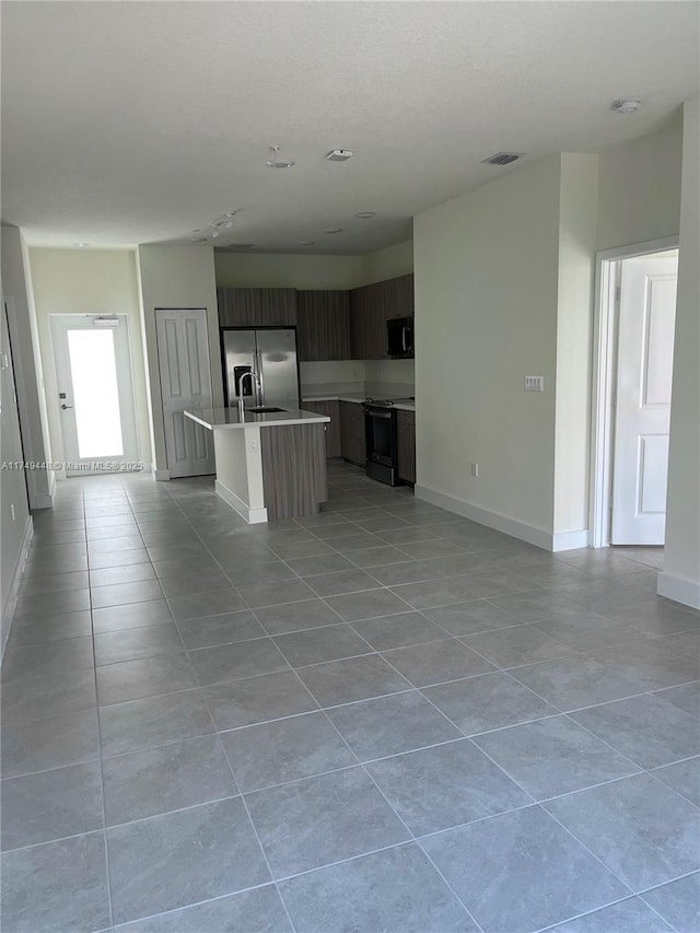 kitchen with open floor plan, light countertops, stainless steel fridge with ice dispenser, an island with sink, and modern cabinets