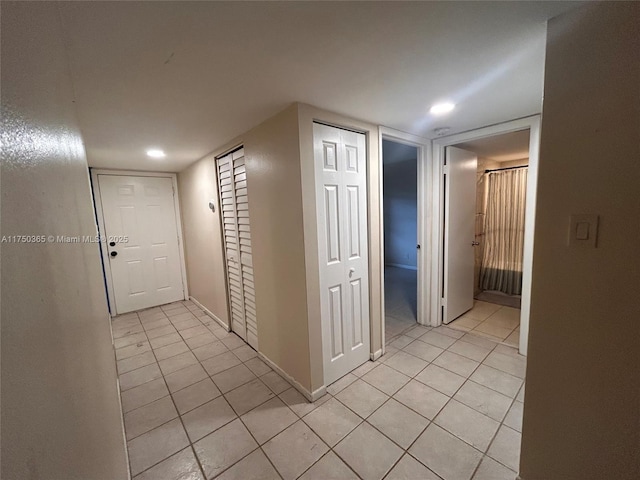 hall featuring recessed lighting, baseboards, and light tile patterned flooring