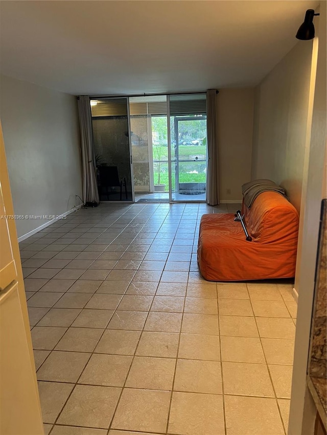 unfurnished living room featuring floor to ceiling windows, light tile patterned flooring, and baseboards