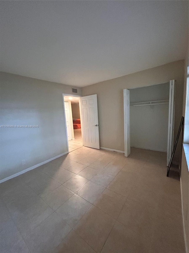 unfurnished bedroom featuring visible vents, baseboards, a closet, and light tile patterned flooring