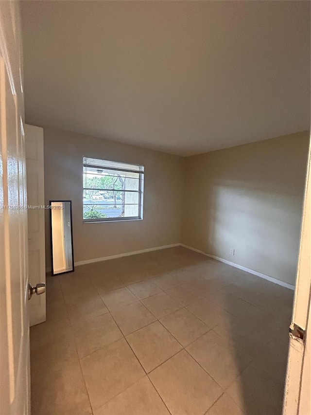 unfurnished room with light tile patterned floors and baseboards