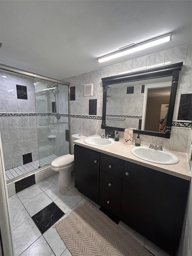 bathroom with a stall shower, visible vents, a sink, and tile walls