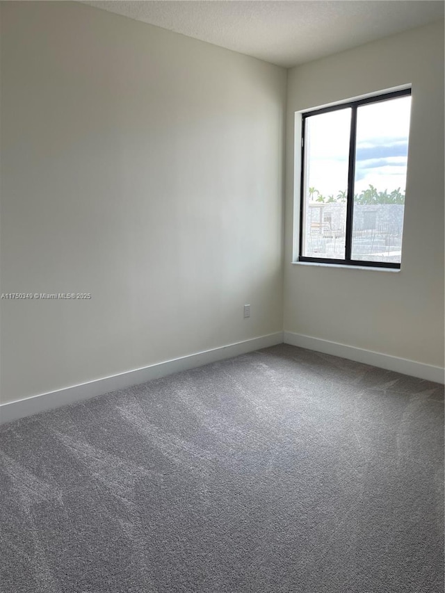 carpeted empty room with a textured ceiling and baseboards