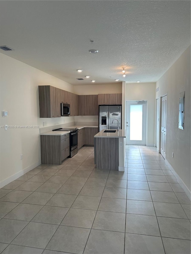 kitchen with a kitchen island with sink, visible vents, light countertops, appliances with stainless steel finishes, and modern cabinets