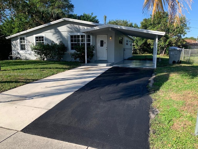 view of front facade featuring an attached carport, a front lawn, and driveway